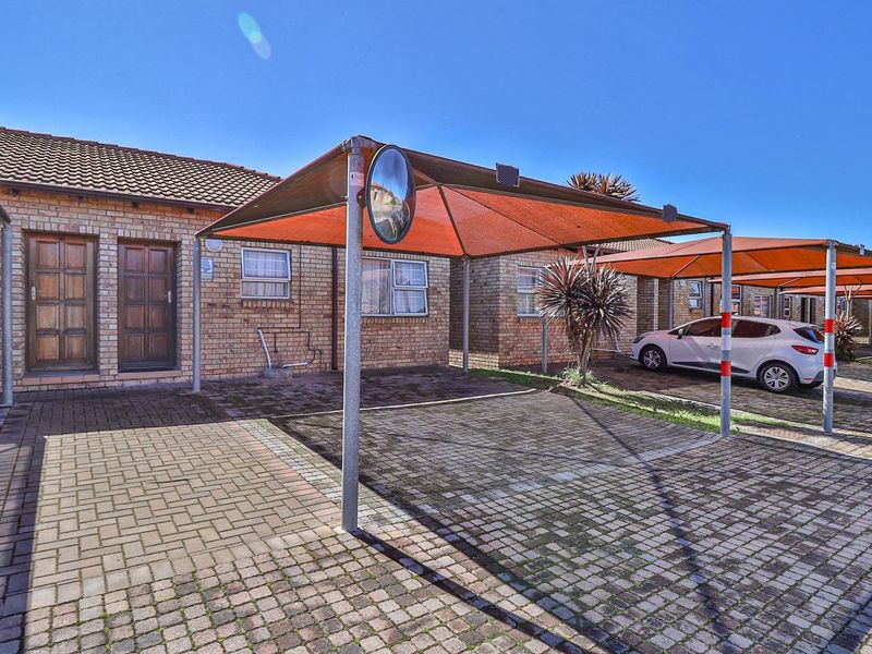 Exterior view of a townhouse complex featuring brick facades, paved driveways, and dedicated shade cloth carports for residents.