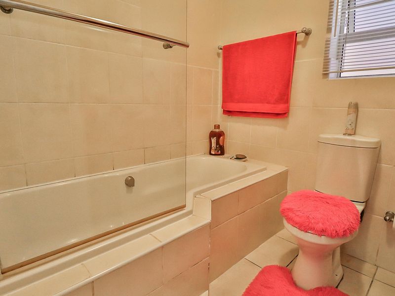 A functional bathroom featuring a built-in bathtub with a glass screen, tiled finishes, and a standard toilet, offering a clean and practical layout.