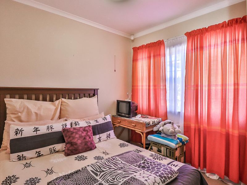 A standard bedroom featuring neutral wall finishes, a built-in cupboard, and window treatments.