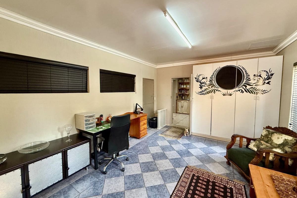 A bedroom featuring tiled flooring, built-in cupboards with decorative detailing, and cornicing, offering a functional space with potential for modern updates.