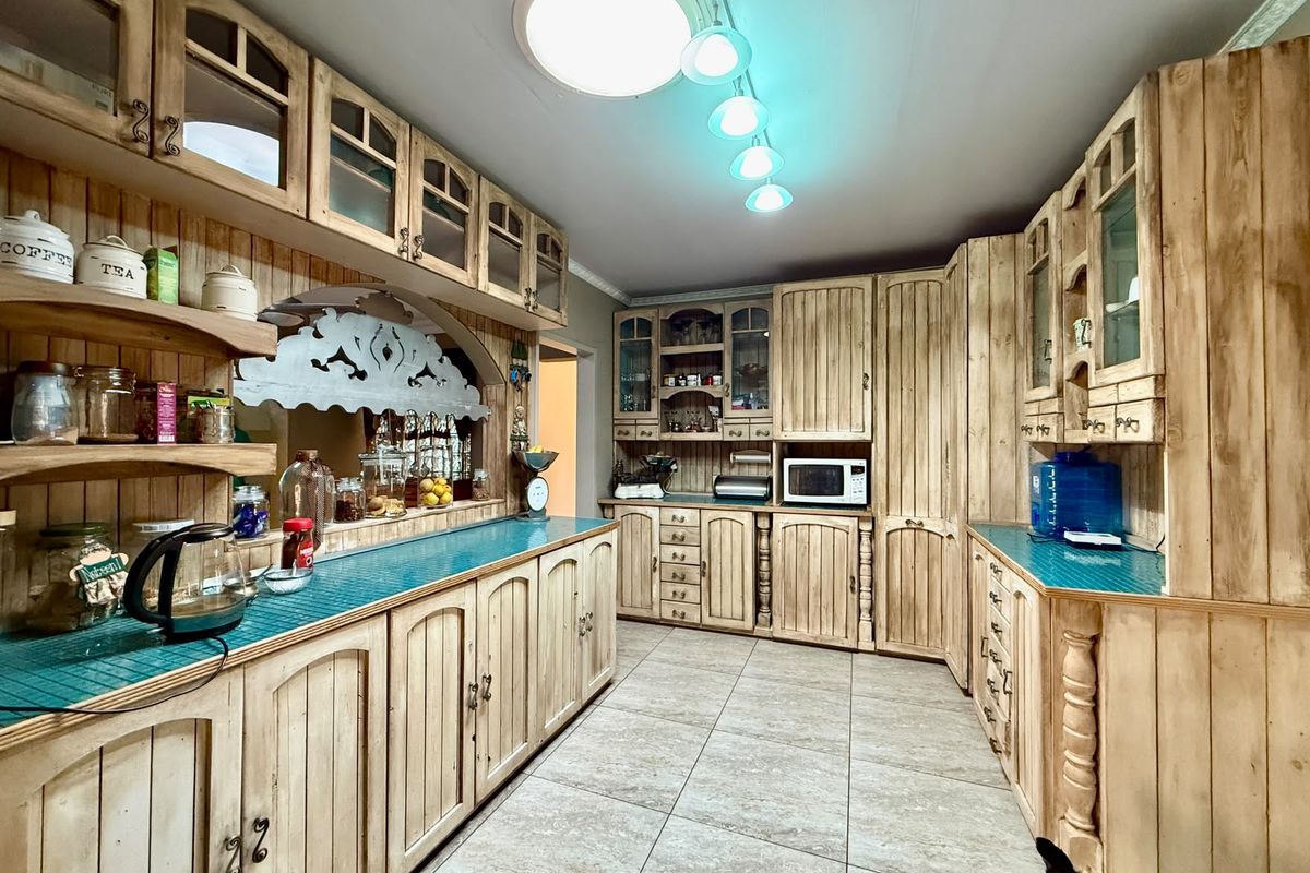 A rustic-style kitchen featuring extensive custom timber cabinetry, tiled flooring, and integrated storage solutions with a warm, traditional aesthetic.
