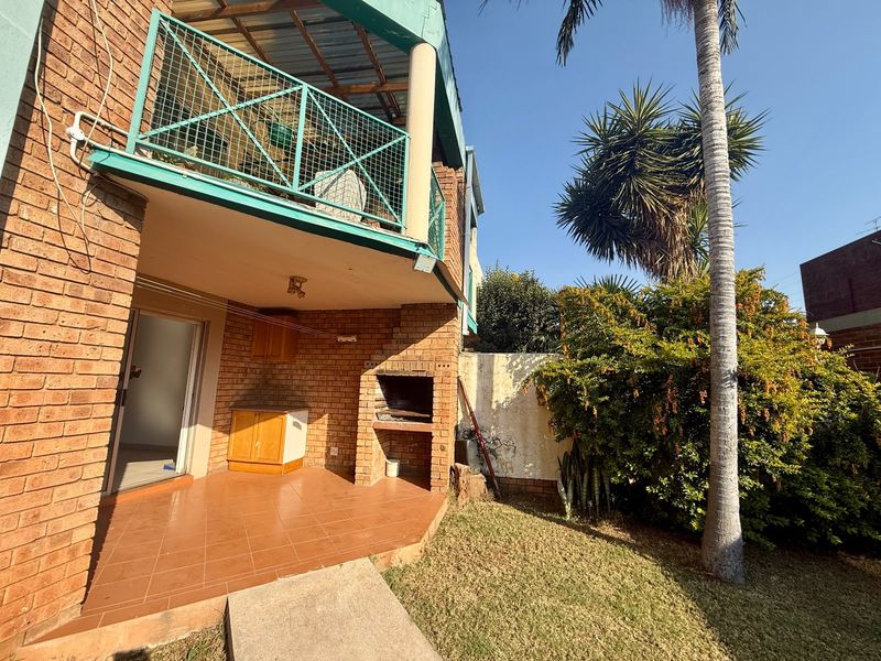 Ground floor patio area featuring a built-in braai, tiled flooring, and direct access to a private garden space.
