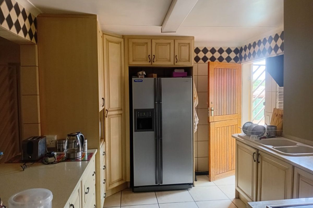 A functional kitchen featuring built-in cabinetry, stone countertops, a double sink, and a classic stable door leading to the exterior.
