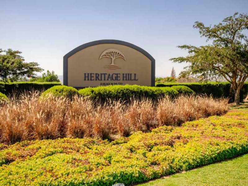 Entrance signage for Heritage Hill estate, featuring well-maintained landscaping and manicured garden beds.