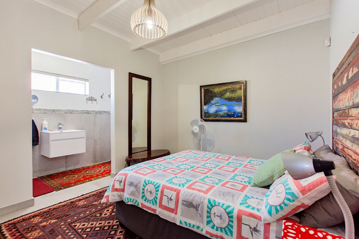 A bedroom featuring exposed timber ceiling beams and an open-plan en-suite bathroom with a modern wall-mounted vanity.