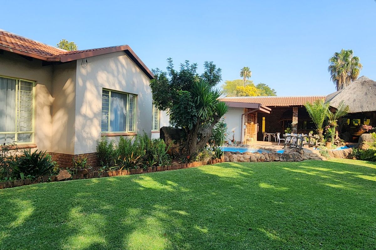 A well-maintained rear garden featuring a swimming pool, a thatched lapa entertainment area, and established landscaping adjacent to the main house.