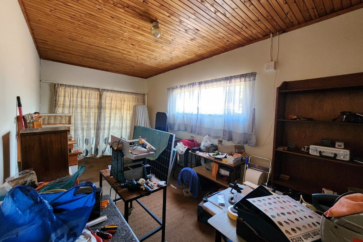 A bedroom featuring a timber tongue and groove ceiling, built-in shelving, and sliding door access, currently used as a workspace.
