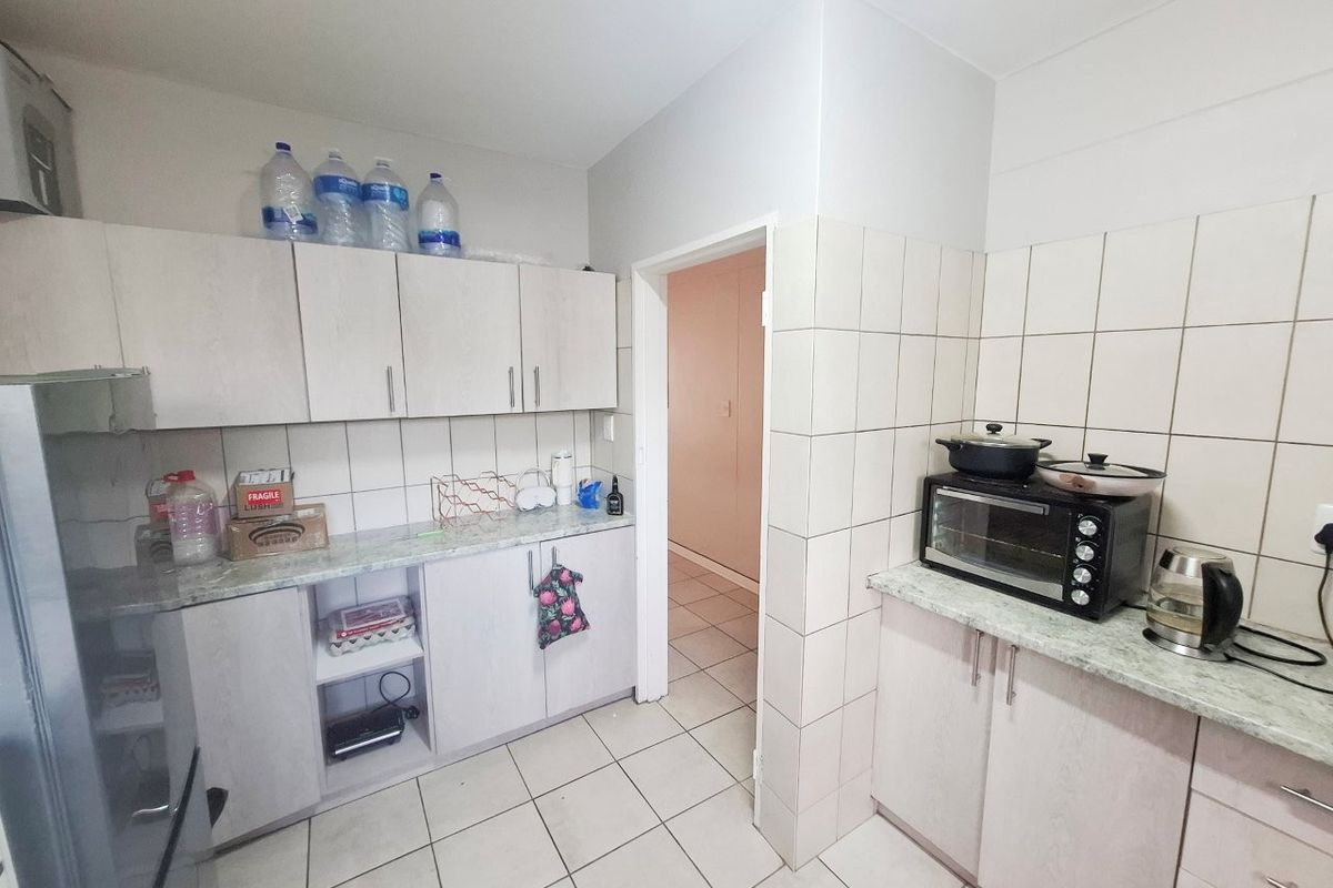 A functional kitchen featuring laminate cabinetry, tiled splashbacks, and tiled flooring, providing a practical workspace with ample storage.