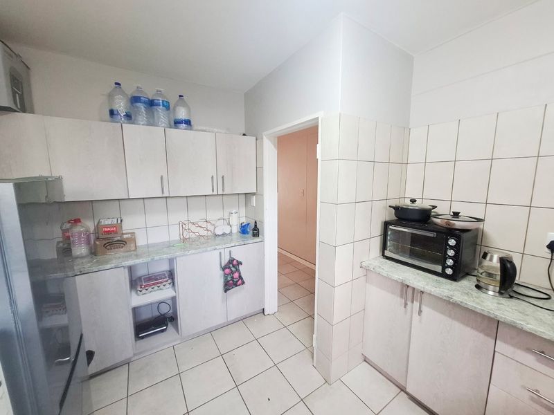 A functional kitchen featuring laminate cabinetry, tiled splashbacks, and tiled flooring, providing a practical workspace with ample storage.