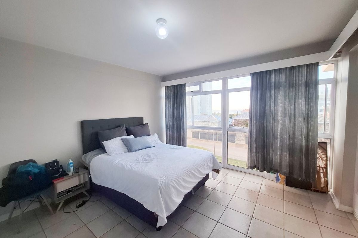 A bedroom featuring tiled flooring and large windows that provide natural light and exterior views.