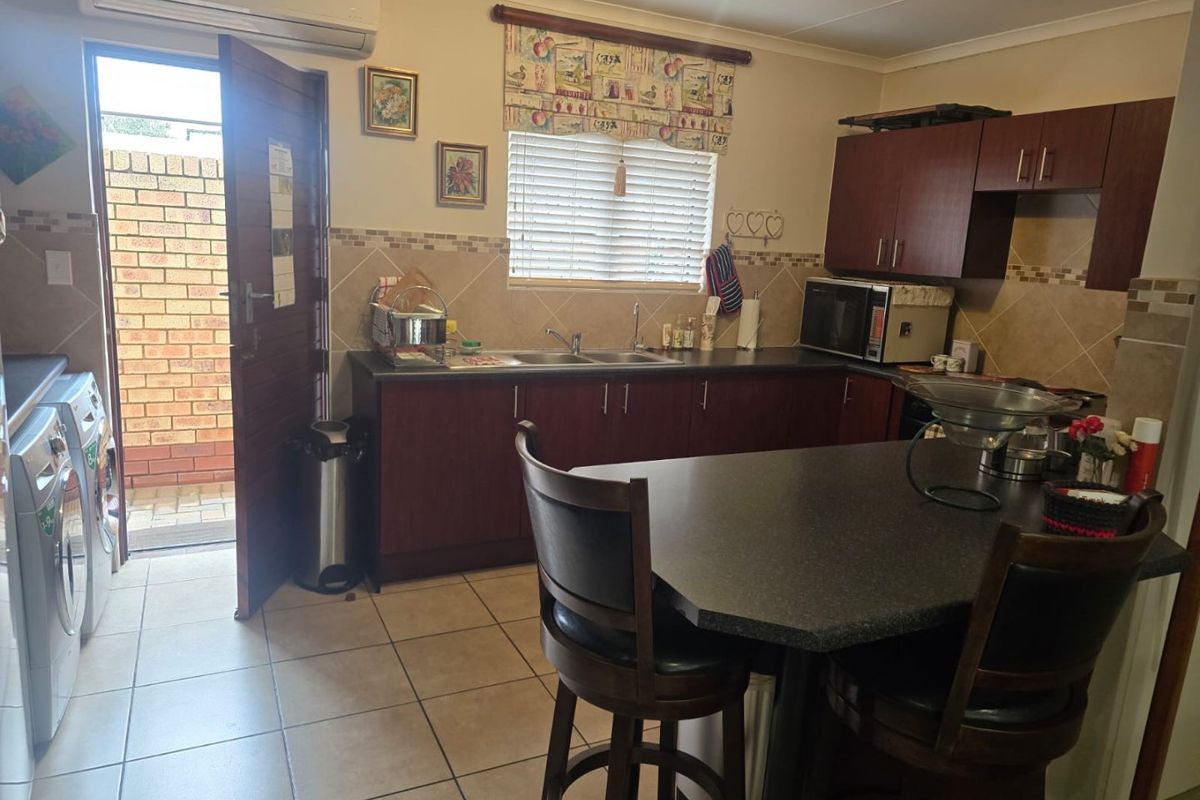 Functional kitchen featuring dark wood cabinetry, laminate countertops, tiled backsplash, and direct access to an outdoor area.