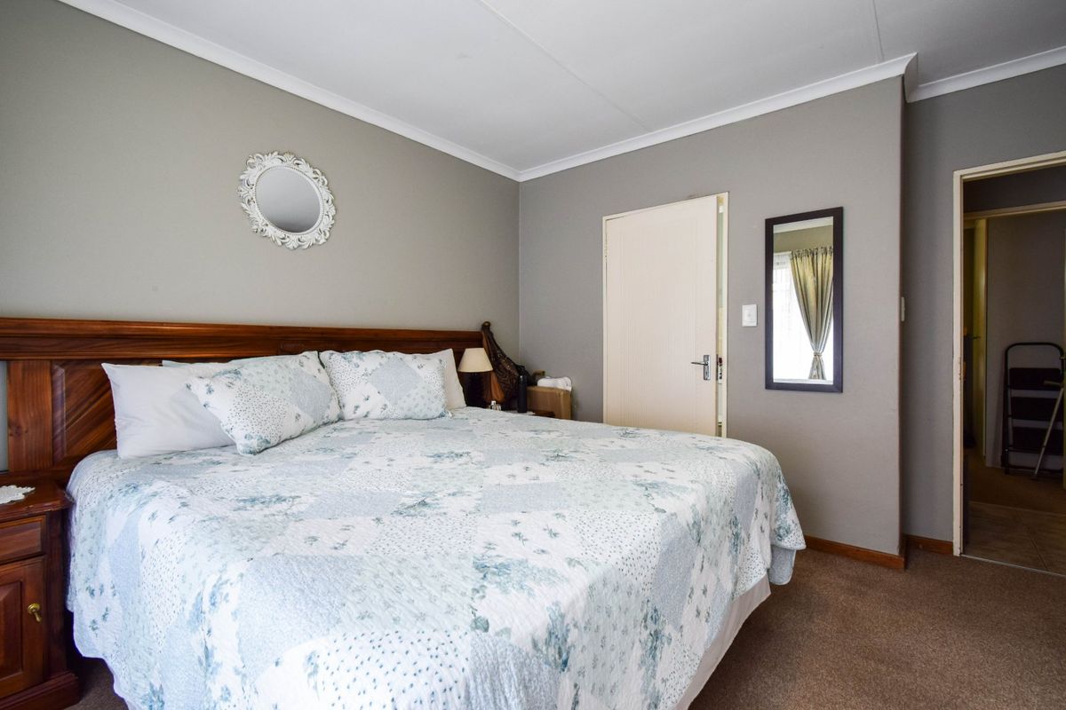 A well-maintained bedroom featuring neutral wall tones, carpeted flooring, and coved ceiling detailing, providing a comfortable and functional living space.