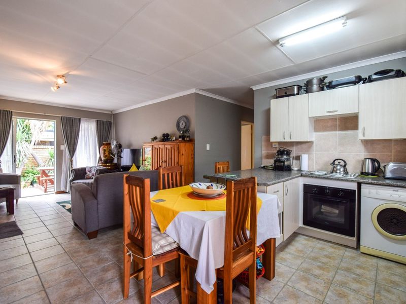Open-plan living and kitchen area featuring tiled floors, granite countertops, built-in oven, and direct access to an outdoor patio through sliding glass doors.