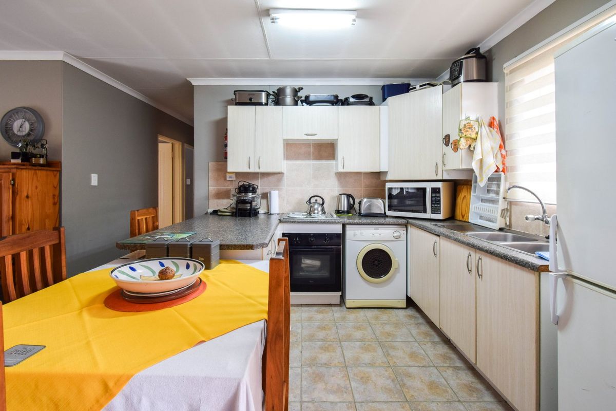 A functional kitchen featuring built-in cabinetry, laminate countertops, a built-in oven and hob, and tiled flooring with a practical layout.