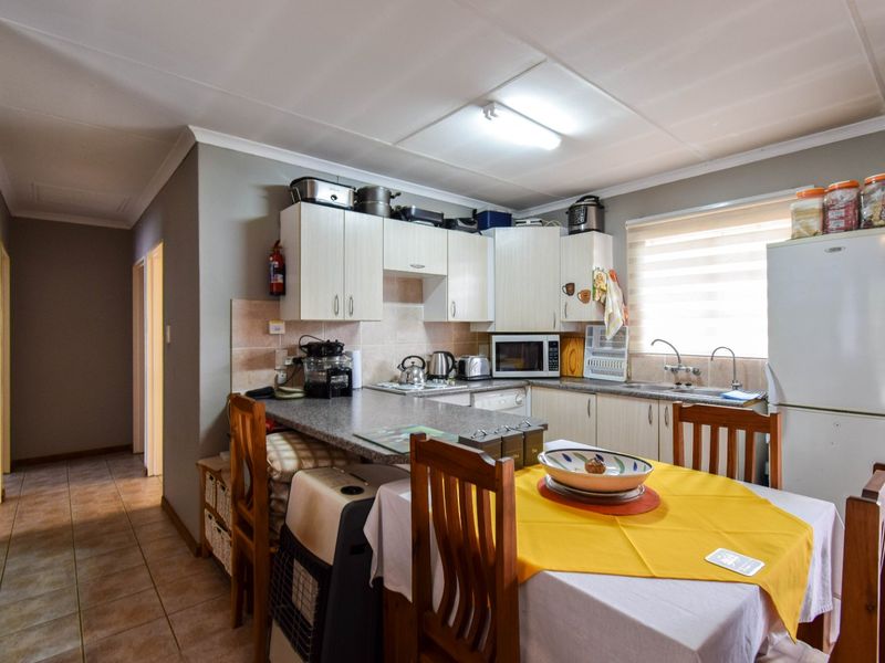 Functional kitchen featuring built-in cabinetry, laminate countertops, tiled backsplash, and a stainless steel sink, with direct access to the hallway.