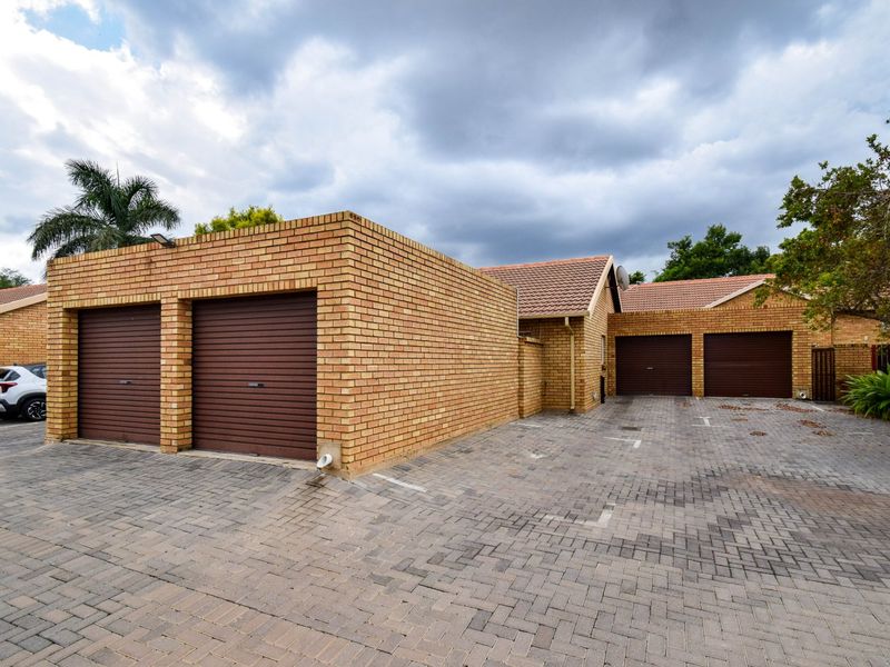 Exterior view of a townhouse complex featuring multiple brick-faced garages and a paved driveway area.