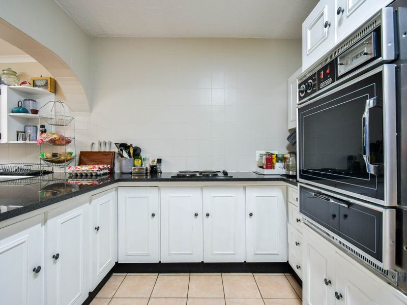 A functional kitchen featuring white cabinetry, black granite countertops, a built-in oven, and a tiled backsplash with a classic layout.