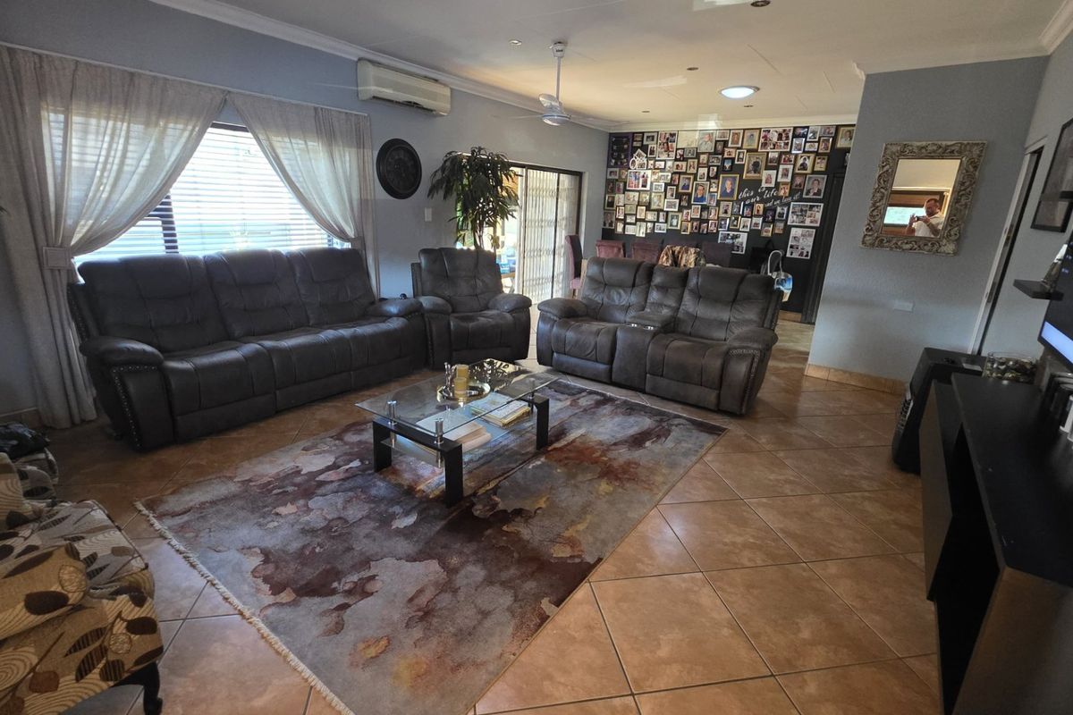 Spacious living room featuring tiled flooring, a ceiling fan, and a wall-mounted air conditioning unit with access to the outdoor area.