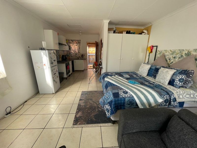 Open-plan studio apartment featuring tiled flooring, a compact kitchen area with built-in cabinetry, and a built-in wardrobe for storage.