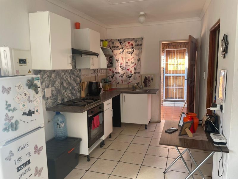 Functional kitchen featuring white cabinetry, built-in oven and hob, tiled flooring, and direct access to an exterior area through a security gate.