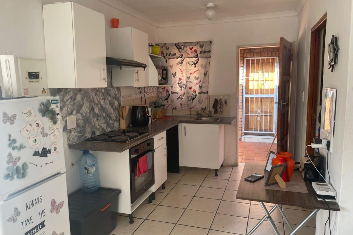 Functional kitchen featuring white cabinetry, built-in oven and hob, tiled flooring, and direct access to an exterior area through a security gate.