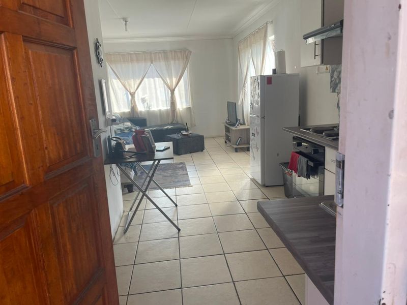 Open-plan living area featuring tiled flooring and a functional kitchen with built-in oven, hob, and extractor fan.