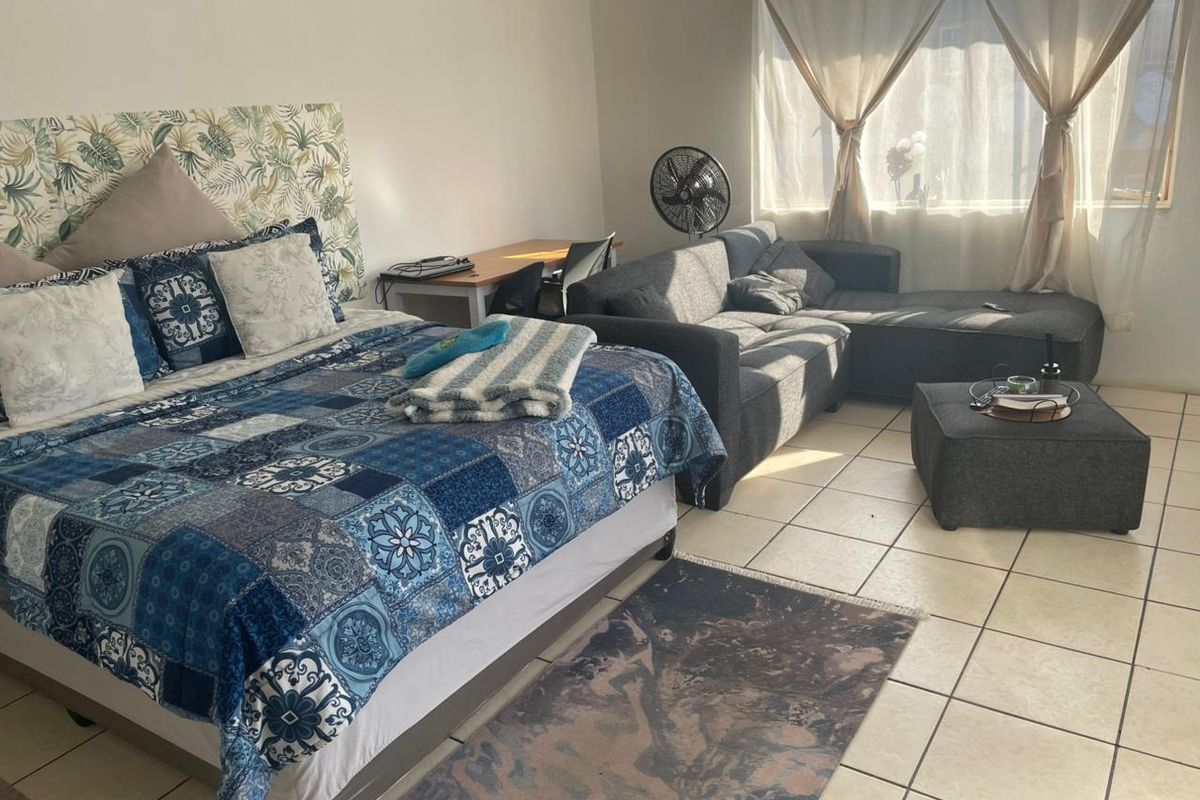 A spacious bedroom featuring ceramic floor tiles and a large window allowing for natural light.
