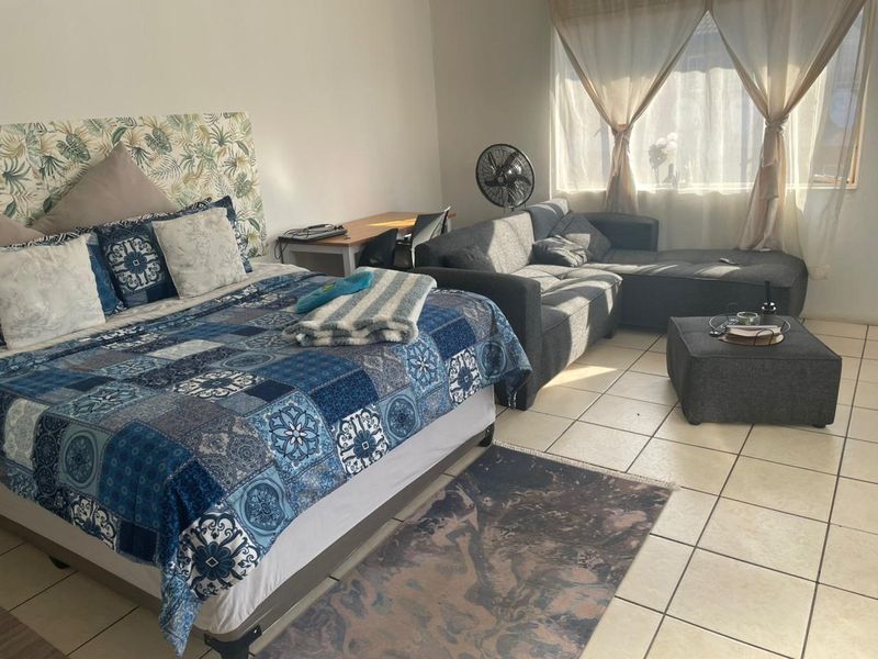 A spacious bedroom featuring ceramic floor tiles and a large window allowing for natural light.