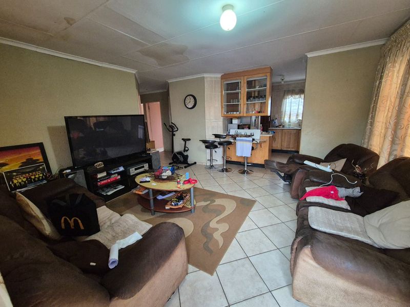 Open plan living area featuring tiled flooring and a breakfast bar, with visible ceiling water damage requiring maintenance and cosmetic updates.