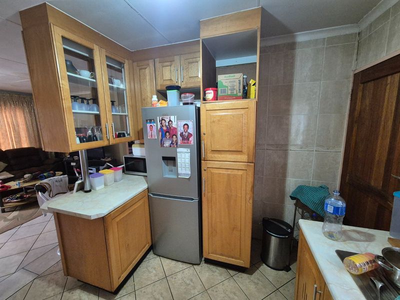 A functional kitchen featuring wooden cabinetry, laminate countertops, and tiled backsplash, offering a practical layout with integrated storage solutions.