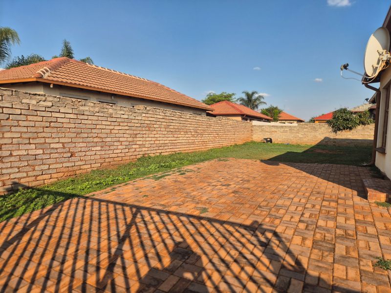 A private rear garden featuring a paved patio area and a brick boundary wall, offering potential for landscaping and outdoor living development.