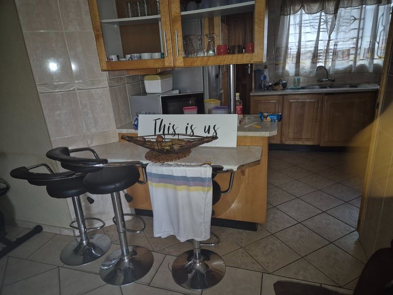 A functional kitchen featuring wooden cabinetry, laminate countertops, a double basin sink, and ceramic floor tiles.