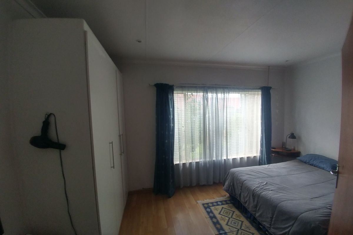 A bedroom featuring laminate flooring and a built-in wardrobe, offering a functional space with natural light through the window.