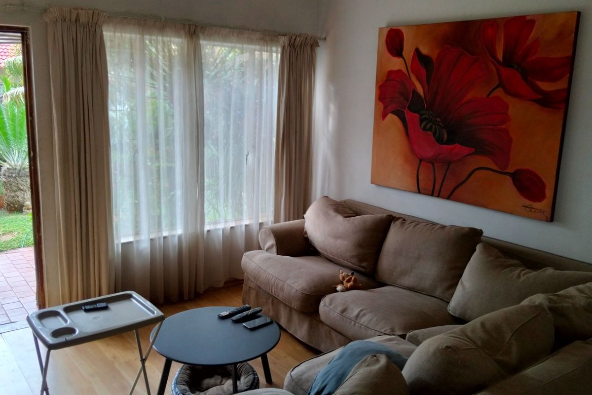 A comfortable living room featuring laminate flooring and a sliding glass door providing direct access to the outdoor patio area.