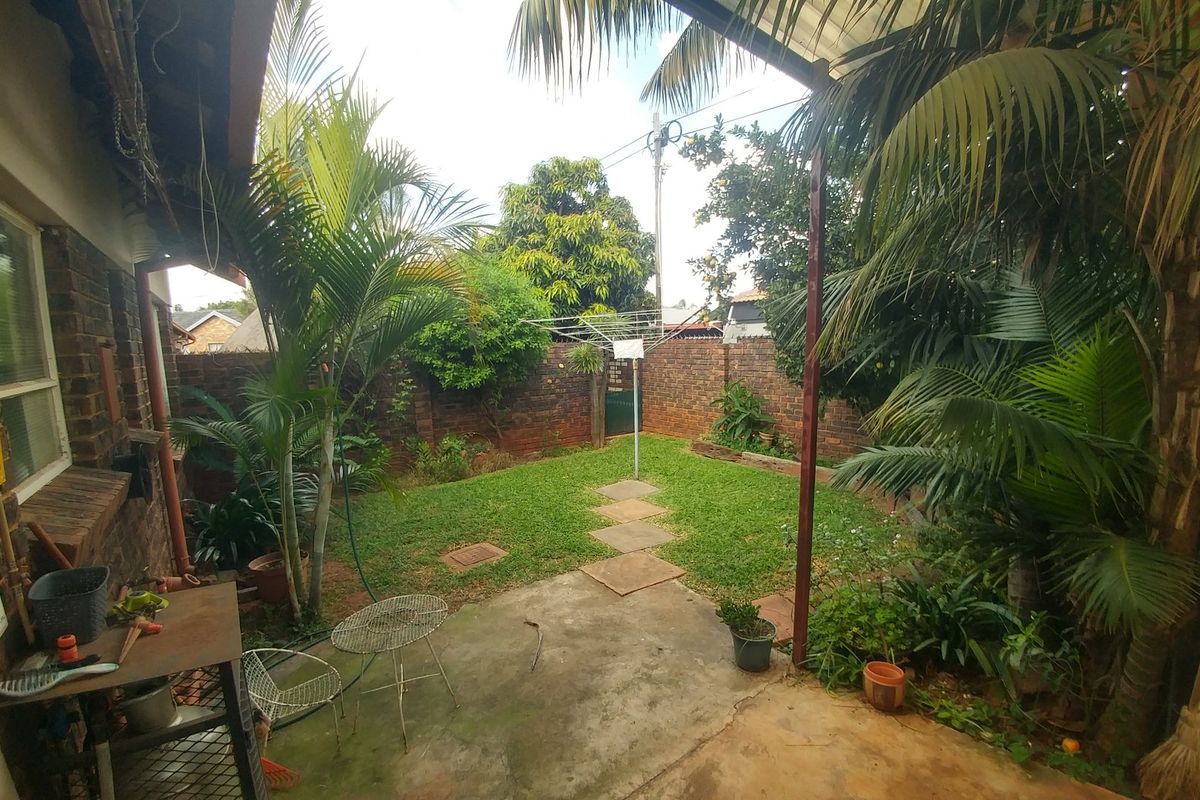 A private rear garden featuring a concrete patio area, established landscaping, brick boundary walls, and a rotary clothesline.