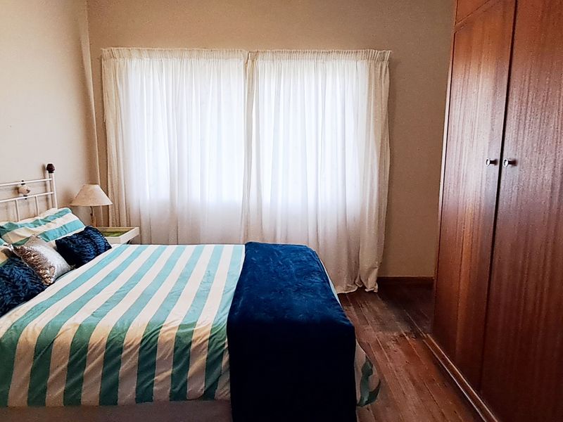 A bedroom featuring timber flooring and a large built-in wooden wardrobe, providing ample storage space.