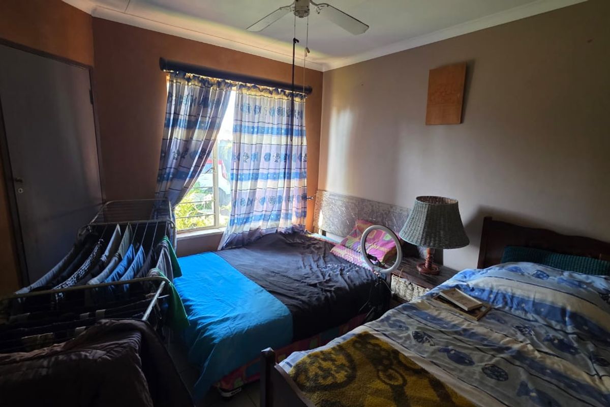 A bedroom featuring a ceiling fan and built-in cupboard storage, offering a functional space with potential for cosmetic updates.