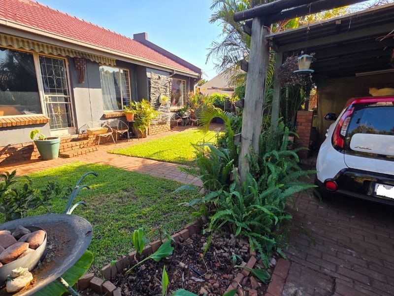 A rear garden area featuring a brick-paved patio, a timber pergola structure, and a tiled roof house exterior.