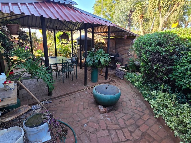 A covered outdoor patio area featuring brick paving and a metal roof, providing a functional space for outdoor relaxation and entertainment.