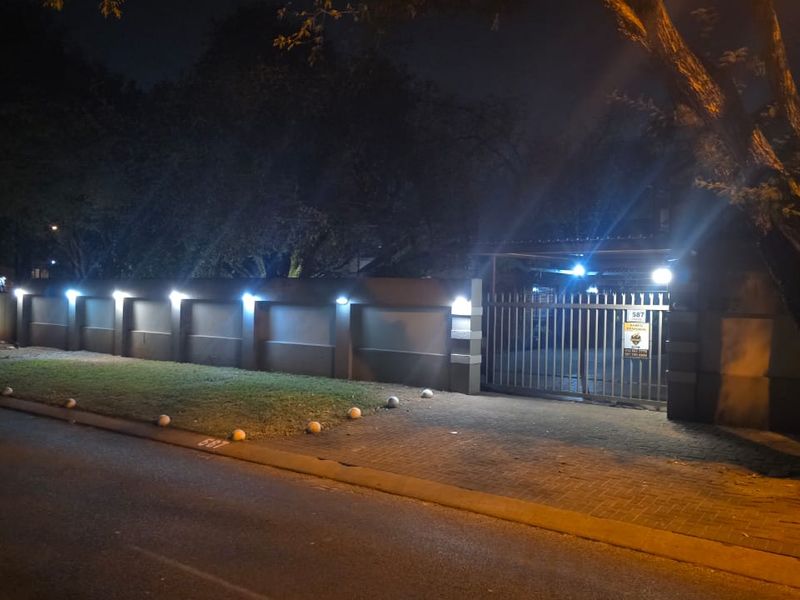 Night view of the property frontage featuring a secure perimeter wall, gated driveway access, and integrated exterior lighting.