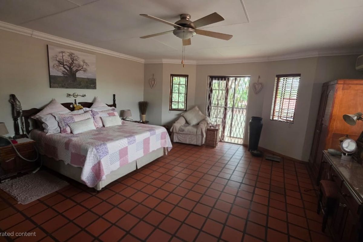 Spacious bedroom featuring terracotta floor tiles, a ceiling fan, and direct access to the outdoors through a security gate.
