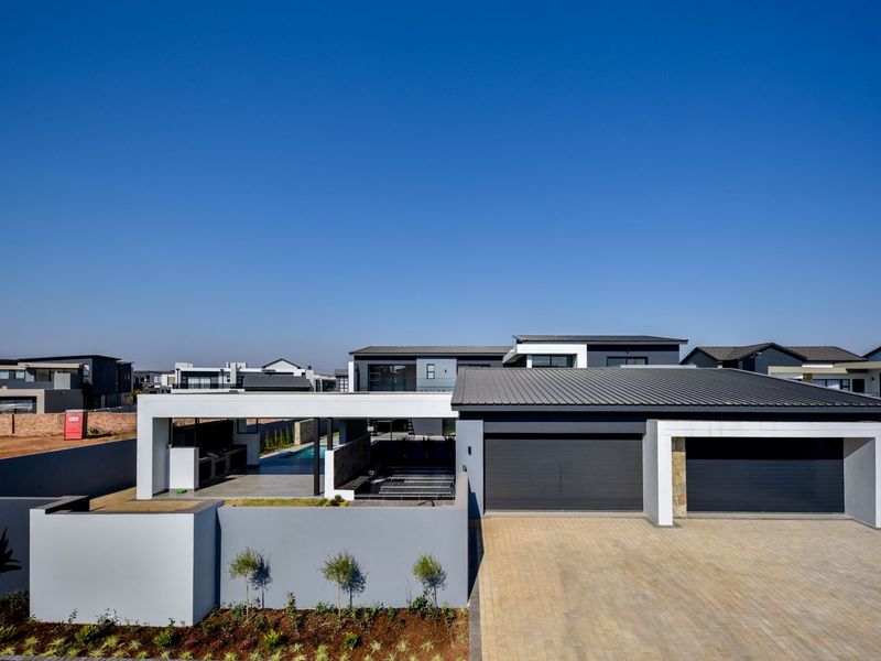 Modern contemporary home featuring a double garage, paved driveway, and a spacious covered patio area with built-in braai facilities.