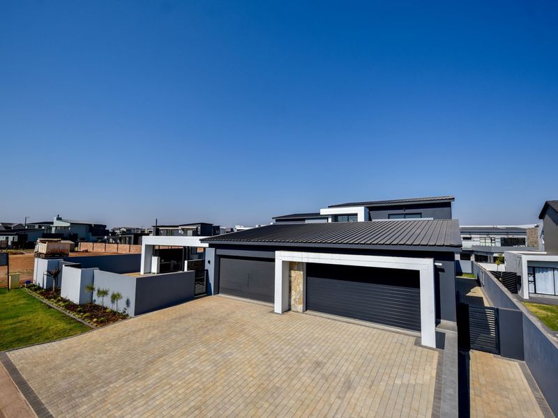 Modern contemporary house exterior featuring a double garage, paved driveway, and clean architectural lines with stone cladding accents.