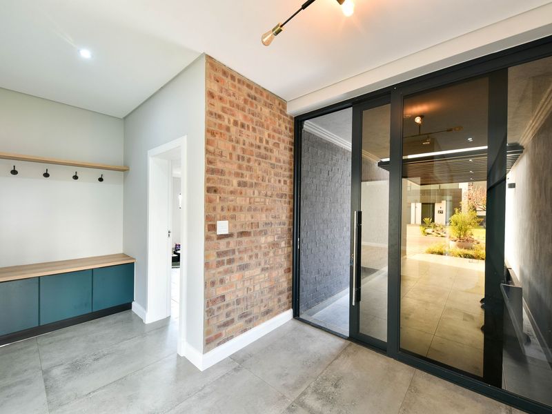 Modern entrance hall featuring an exposed brick wall, built-in storage cabinetry, and large sliding glass doors leading to an outdoor patio area.