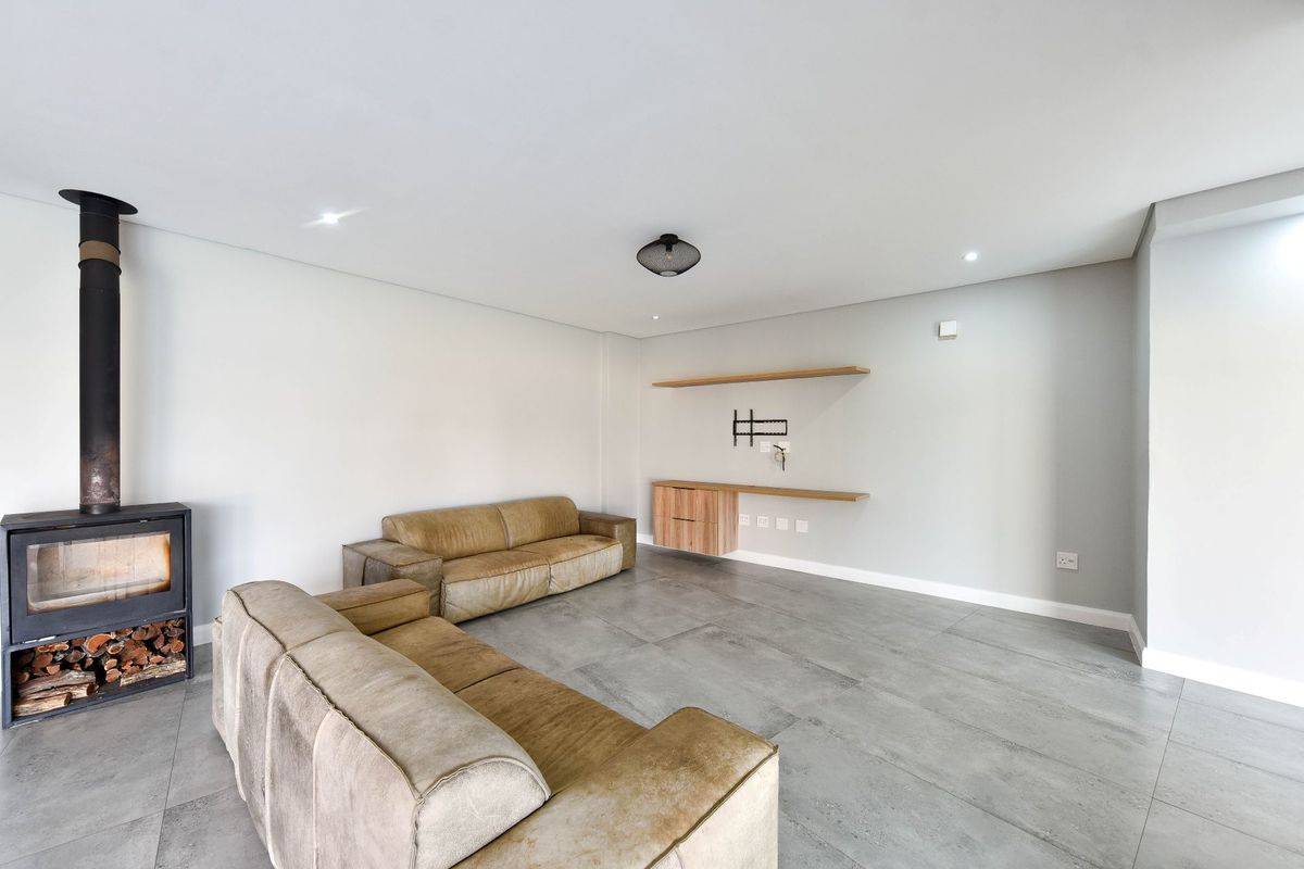 Modern living room featuring large format floor tiles, a contemporary freestanding fireplace, and built-in wall shelving with integrated media connections.