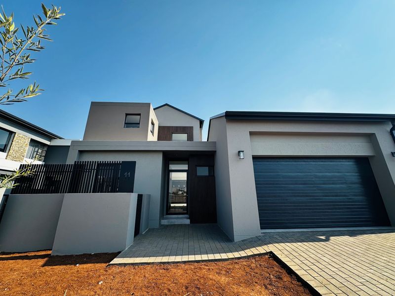 Modern front elevation featuring a double garage, paved driveway, and contemporary architectural design with clean lines and neutral finishes.