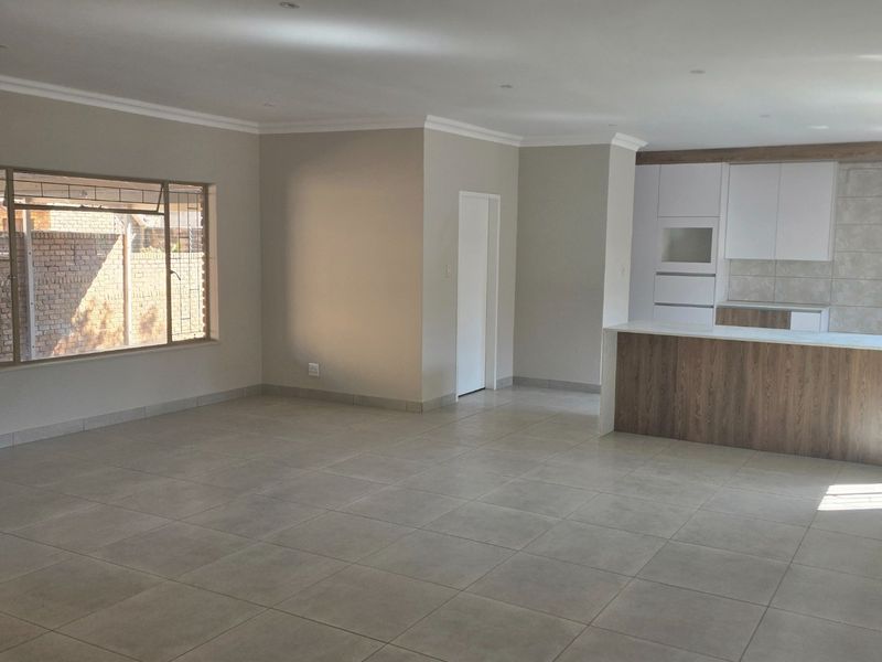 Spacious open-plan living area featuring modern tiled floors, recessed lighting, and a contemporary kitchen with a central island and built-in cabinetry.