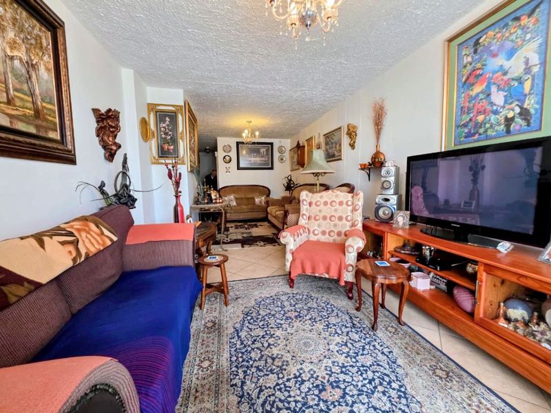 A spacious living room featuring tiled flooring and a textured ceiling, offering a comfortable area for relaxation and entertainment.