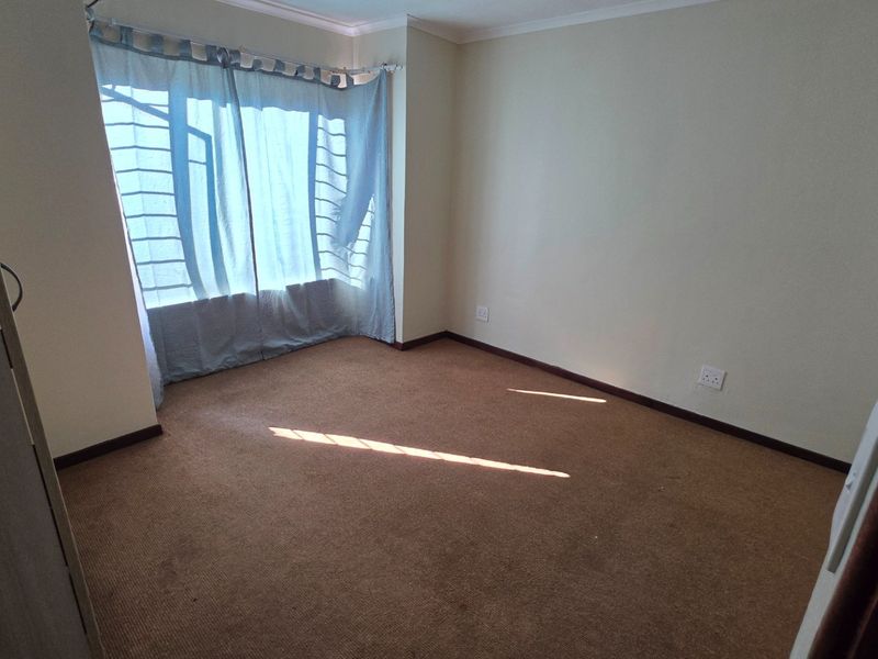 A vacant bedroom featuring carpeted flooring and a large window, providing a blank canvas for personalization.