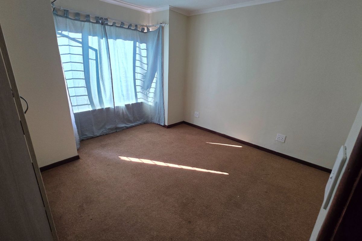 A vacant bedroom featuring carpeted flooring and a large window, providing a blank canvas for personalization.